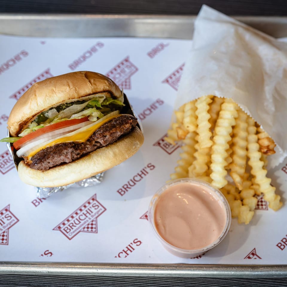 Bruchi's cheeseburger with fries and dipping sauce on branded paper.