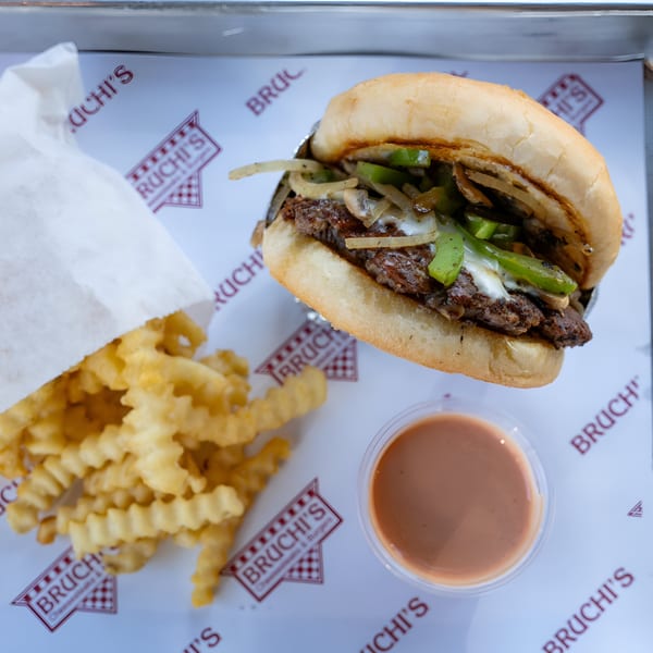 Bruchi's cheesesteak with green peppers, onions, and mushrooms, crinkle-cut fries, and dipping sauce.